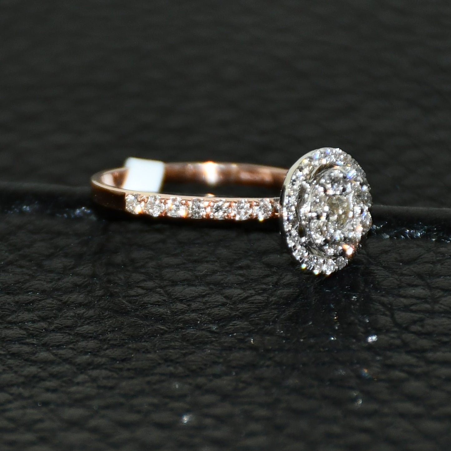 A diamond ring is displayed on a black leathered surface.