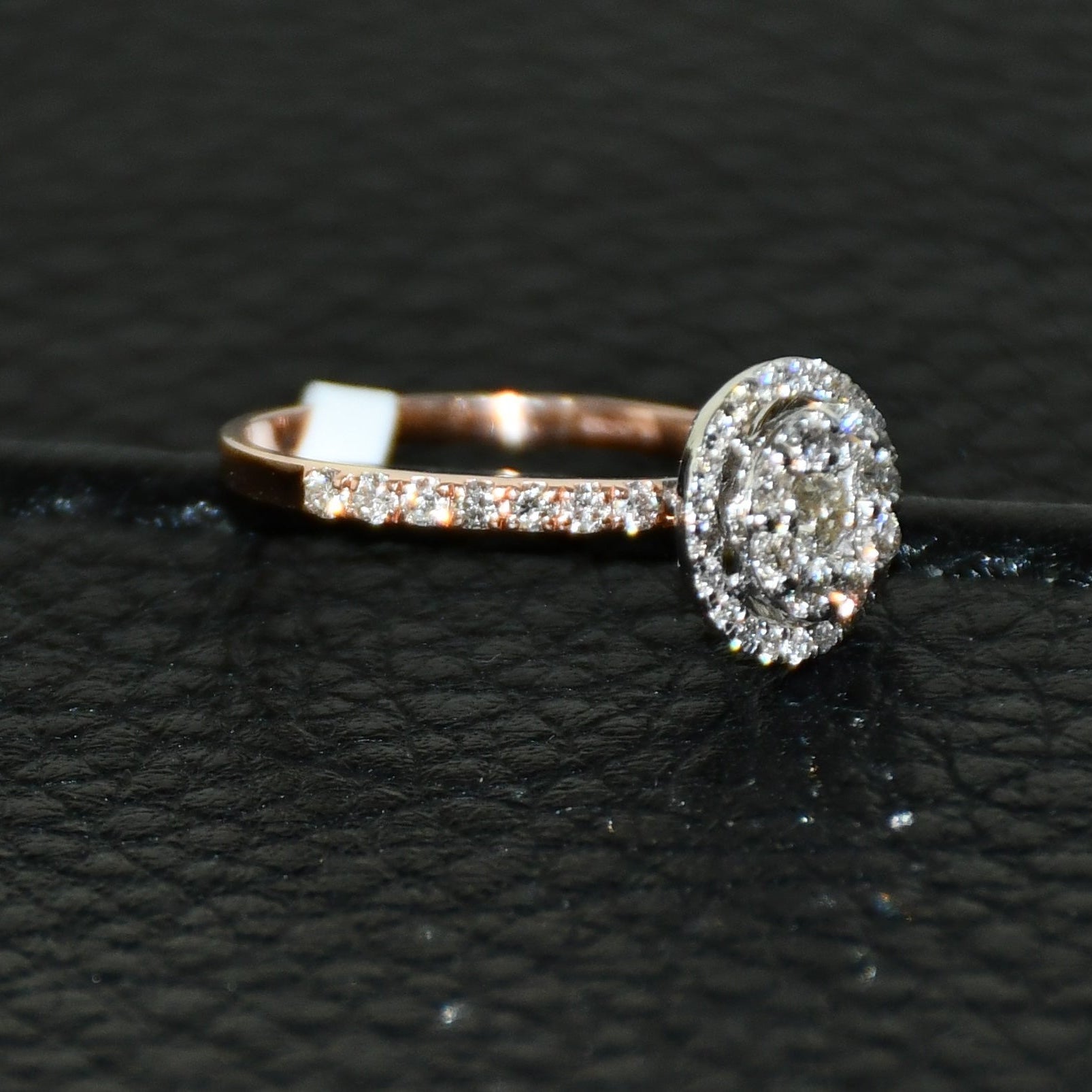 A diamond ring is displayed on a black leathered surface.