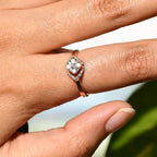 A person's hand displaying a gold ring with a central diamond surrounded by smaller diamonds set in a solid gold band.