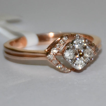 A gold ring with a central diamond surrounded by smaller diamonds set in a solid gold band is displayed on a white surface.
