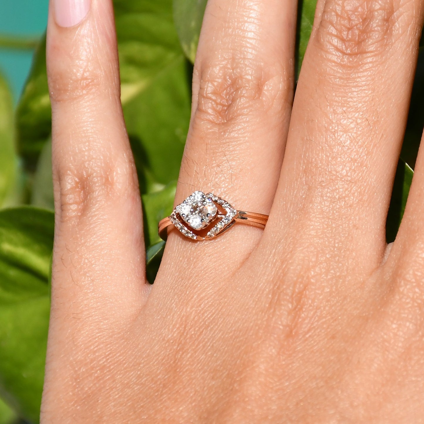 A person's hand displaying a gold ring with a central diamond surrounded by smaller diamonds set in a solid gold band.