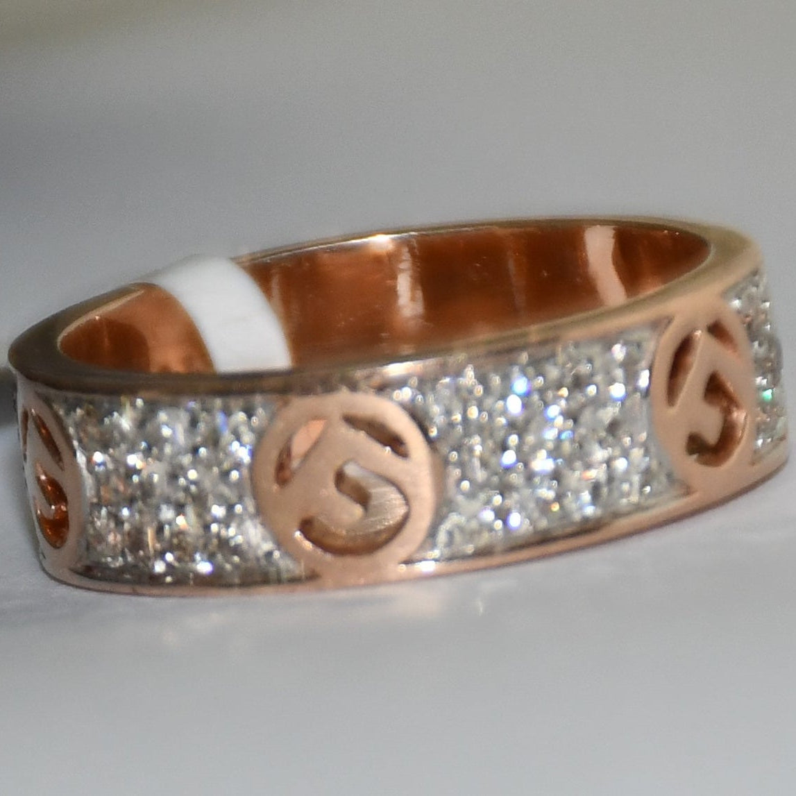 A 14kt gold diamond band ring with smaller diamonds, set on a gold band displayed on a white surface.