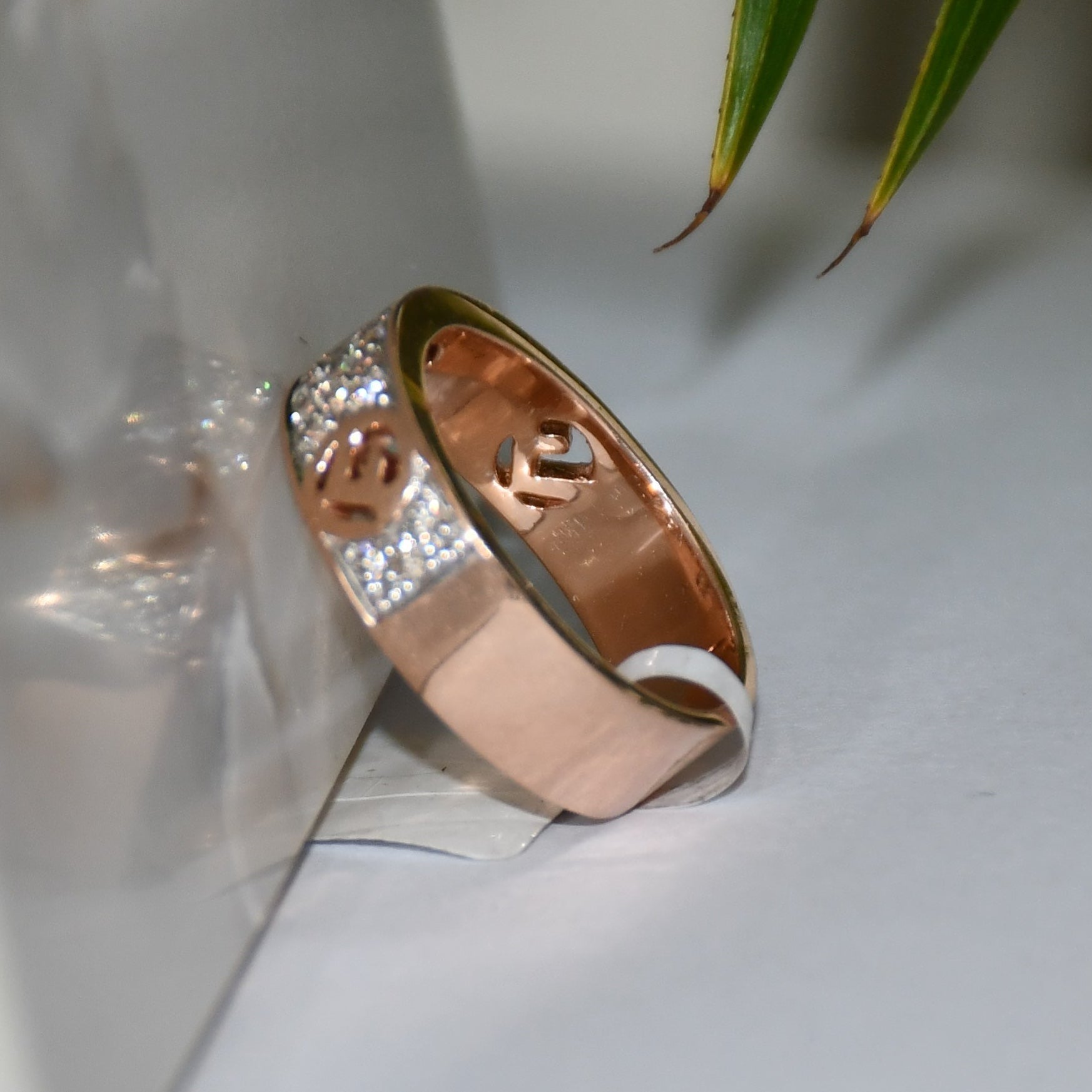A 14kt gold diamond band ring with smaller diamonds, set on a gold band displayed on a white surface against a reflective surface.