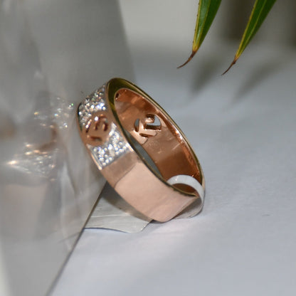 A 14kt gold diamond band ring with smaller diamonds, set on a gold band displayed on a white surface against a reflective surface.