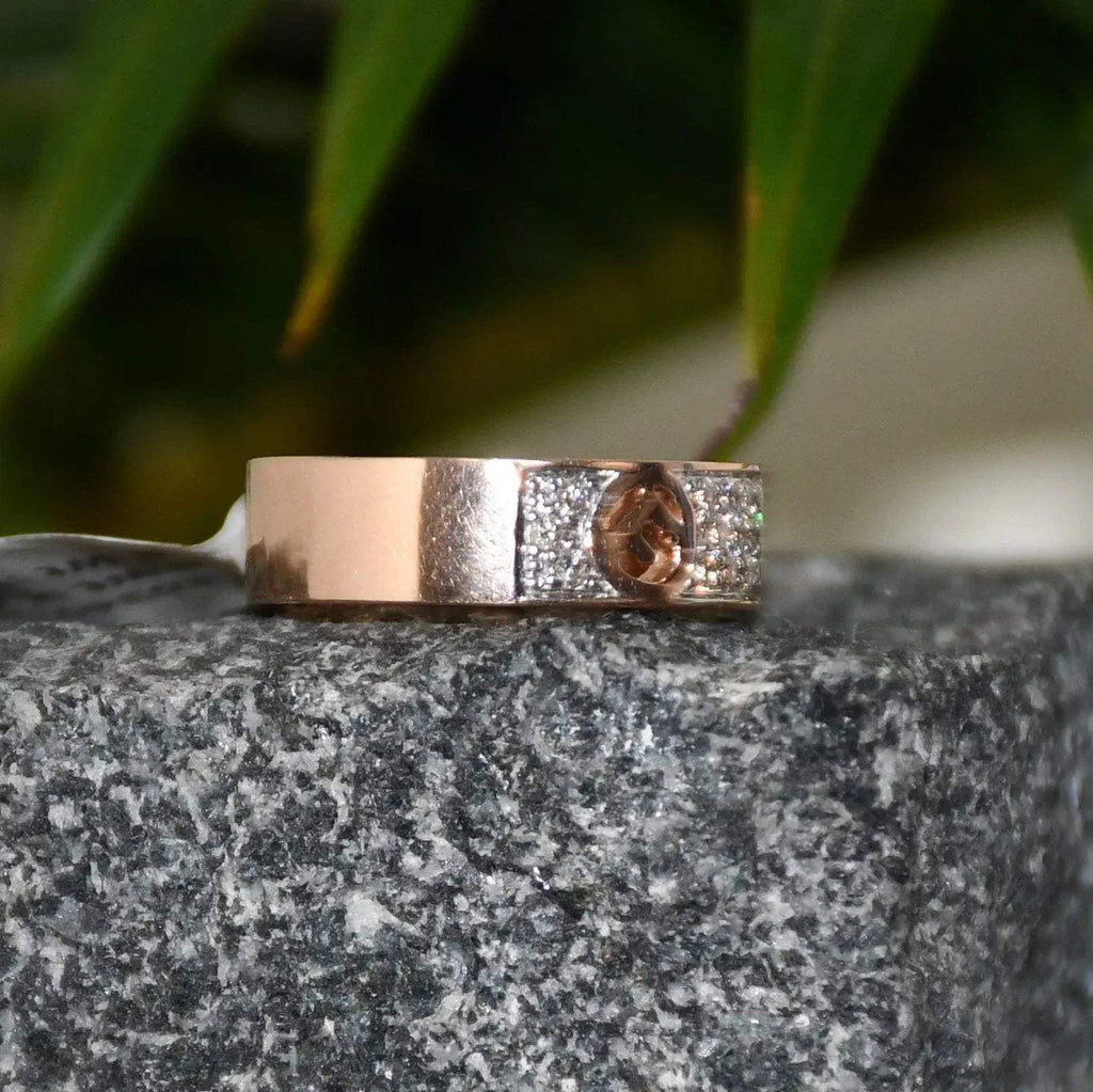 A 14kt gold diamond band ring with smaller diamonds, set on a gold band displayed on a rough textured surface.
