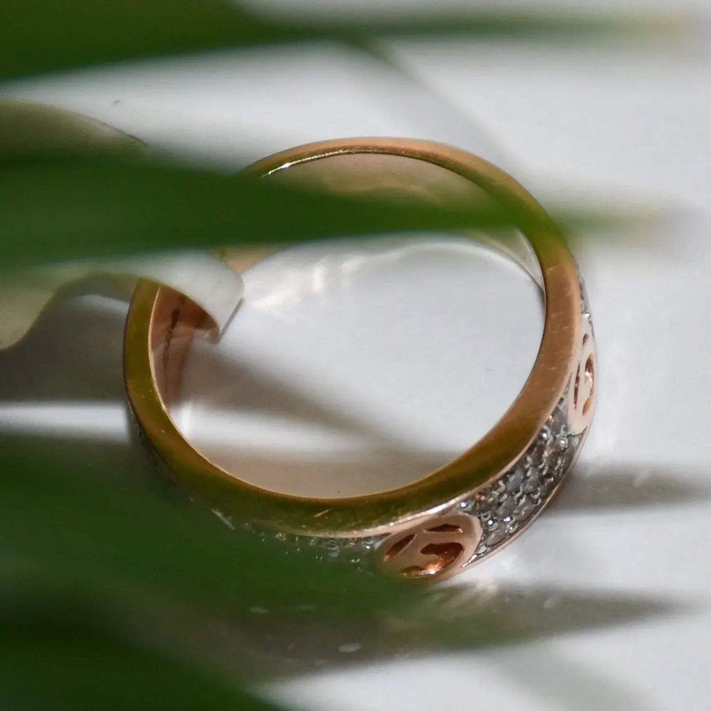 A 14kt gold diamond band ring with smaller diamonds, set on a gold band displayed on a white surface.
