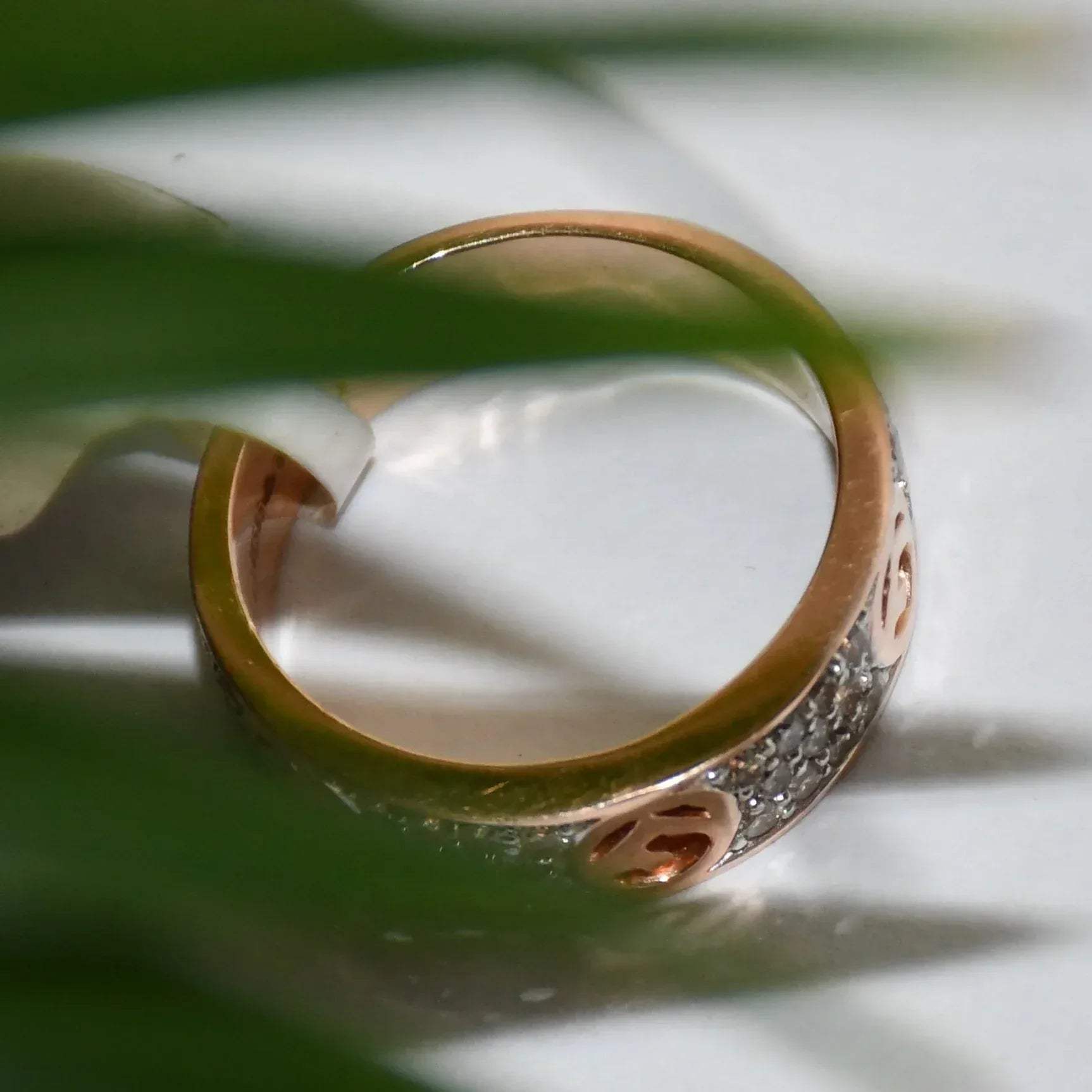 A 14kt gold diamond band ring with smaller diamonds, set on a gold band displayed on a white surface.
