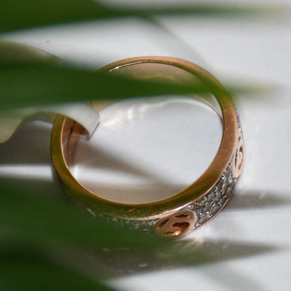 A 14kt gold diamond band ring with smaller diamonds, set on a gold band displayed on a white surface.