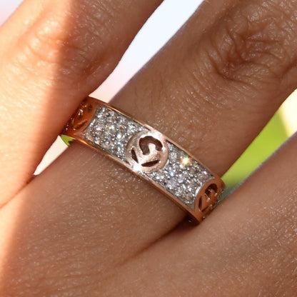 A person's hand displaying a 14kt gold diamond band ring with smaller diamonds, set on a gold band.