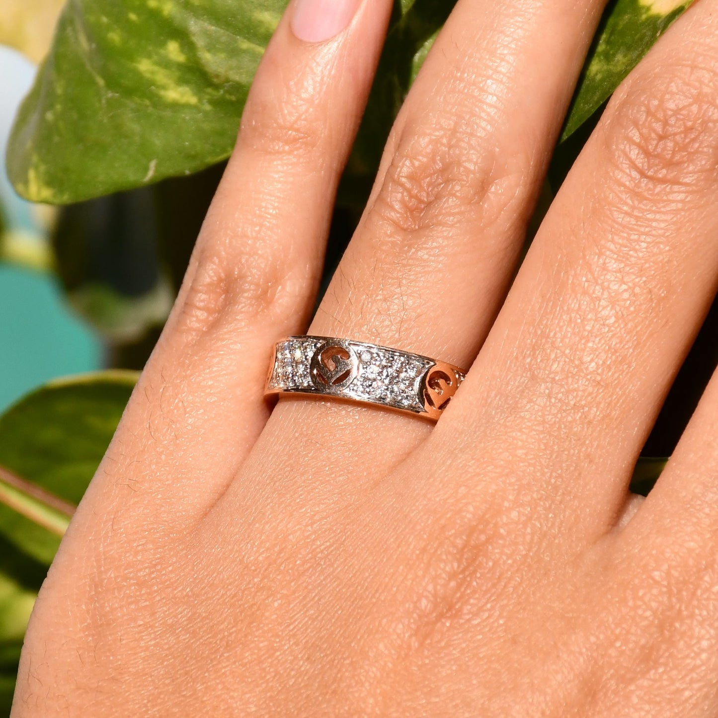 A 14kt gold diamond band ring with smaller diamonds, set on a gold band displayed on a person's hand.