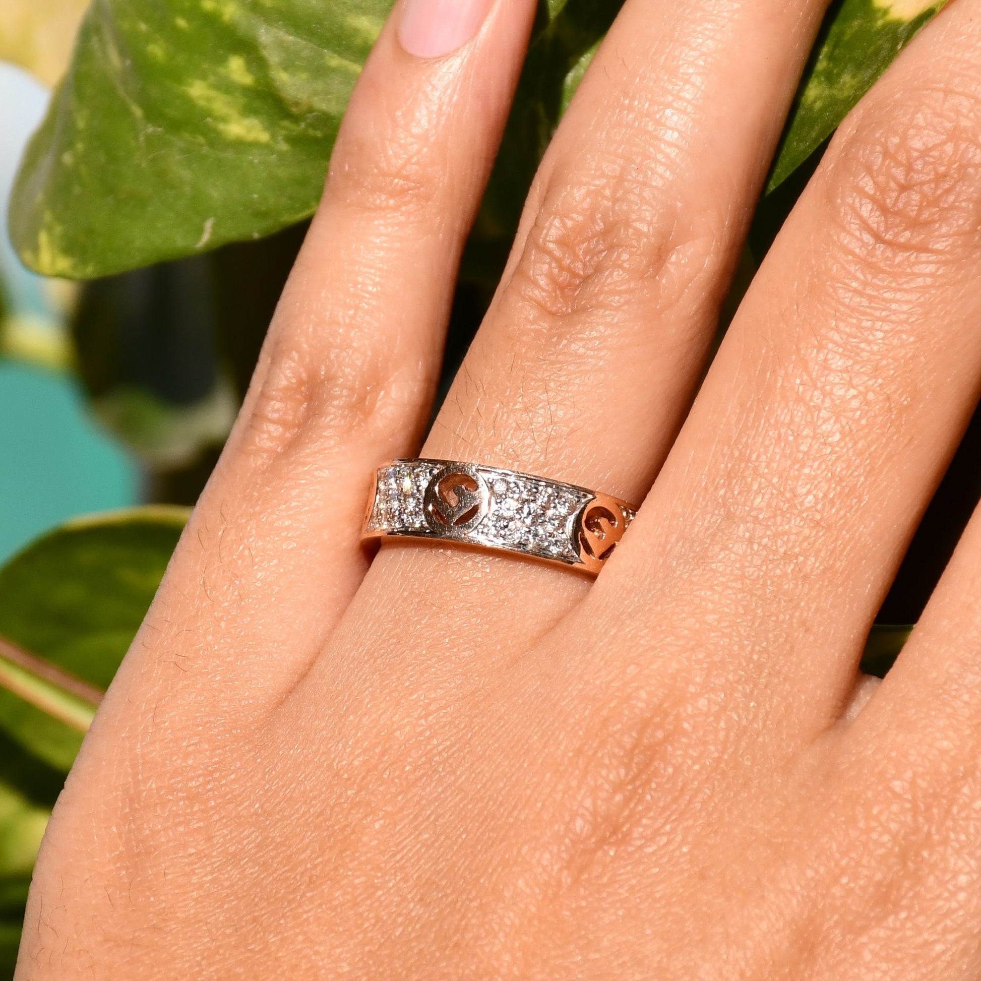 A 14kt gold diamond band ring with smaller diamonds, set on a gold band displayed on a person's hand.
