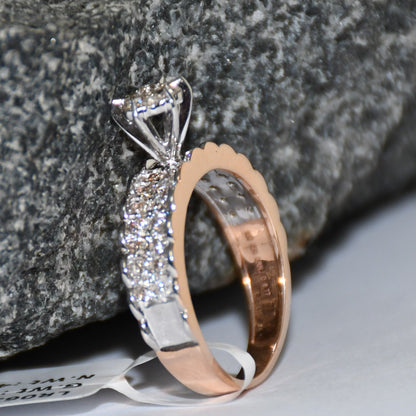 A 14K gold diamond band ring with a clear, certified diamond centerpiece displayed standing against a black and grey rough background.