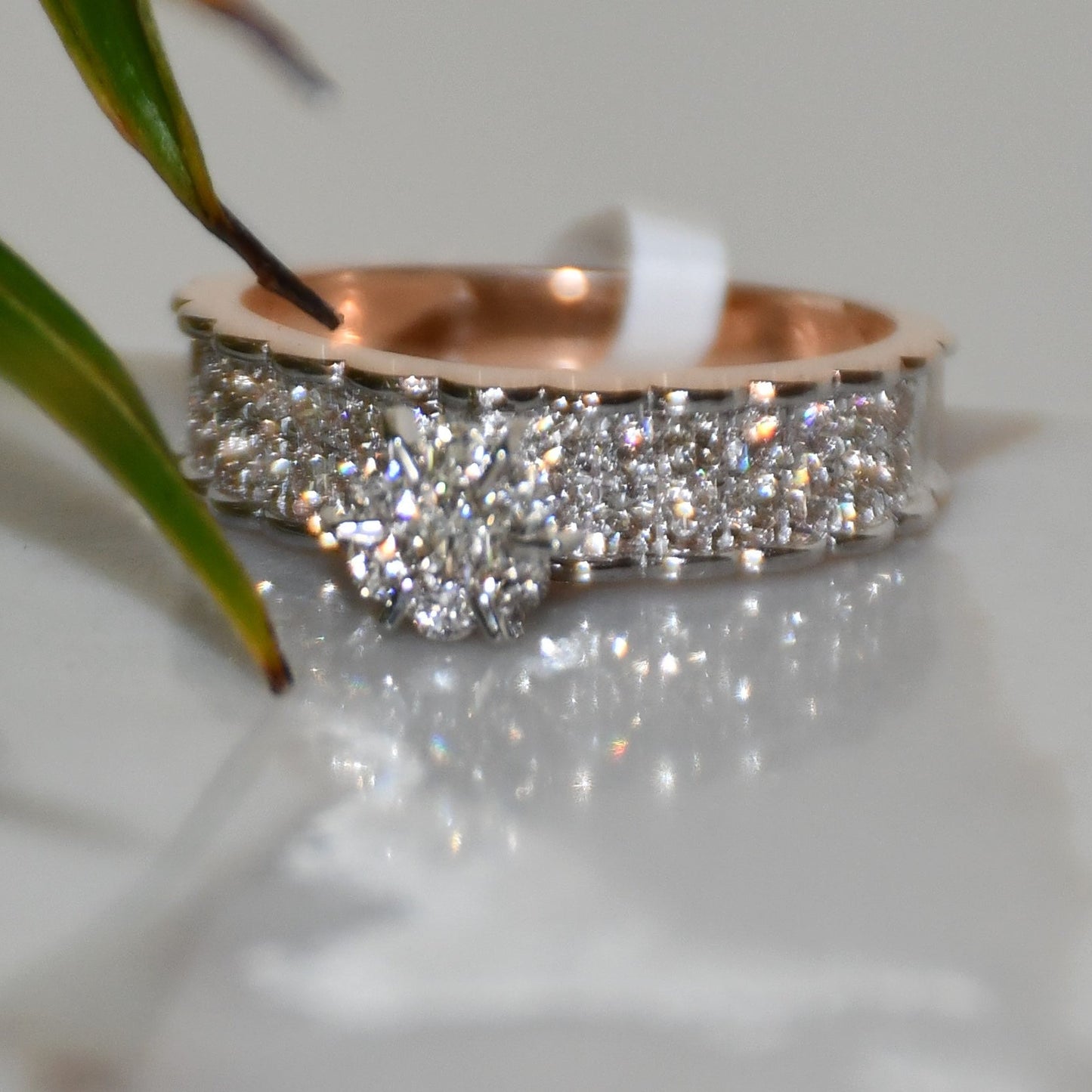 A 14K gold diamond band ring with a clear, certified diamond centerpiece displayed on a white reflective background.