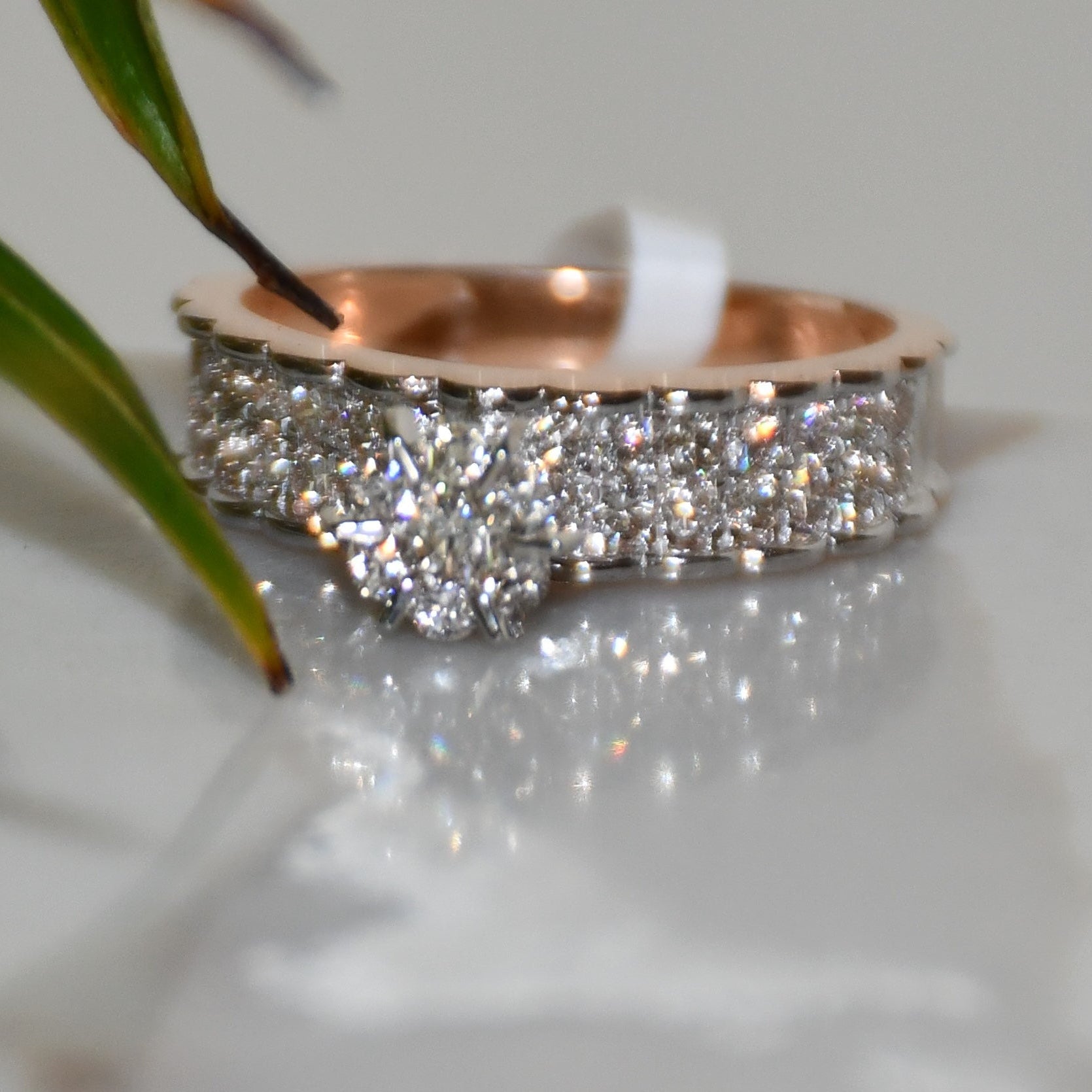 A 14K gold diamond band ring with a clear, certified diamond centerpiece displayed on a white reflective background.