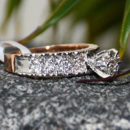 A 14K gold diamond band ring with a clear, certified diamond centerpiece displayed on a black and grey rough surface.