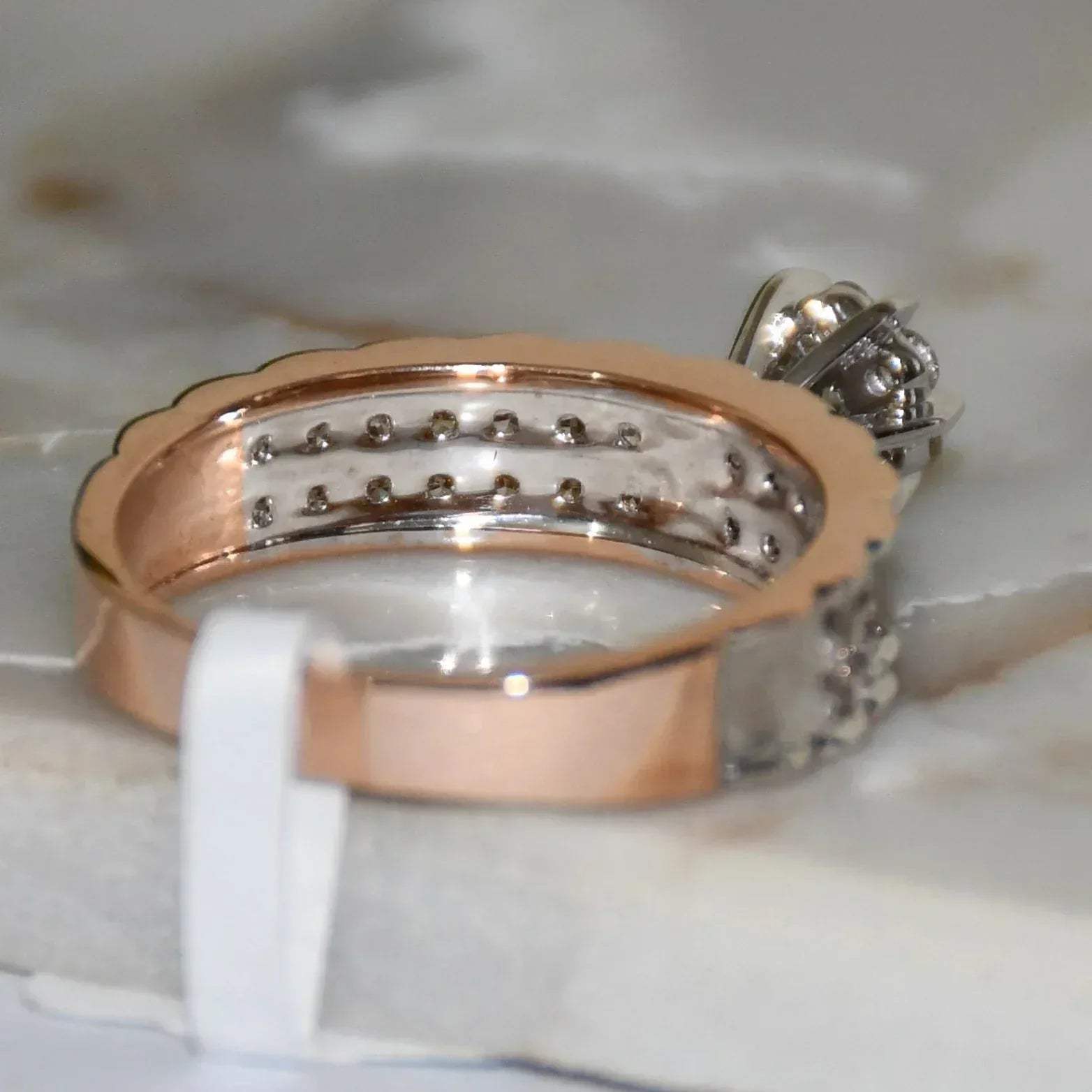 A 14K gold diamond band ring with a clear, certified diamond centerpiece displayed on a white smooth surface.