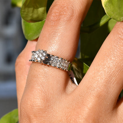 A person's hand holding a 14K gold diamond band ring with a clear, certified diamond centerpiece.