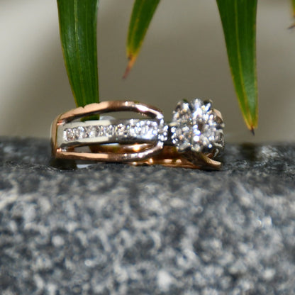 A diamond band ring with 14K gold hallmark, displayed on a black and grey rough surface.