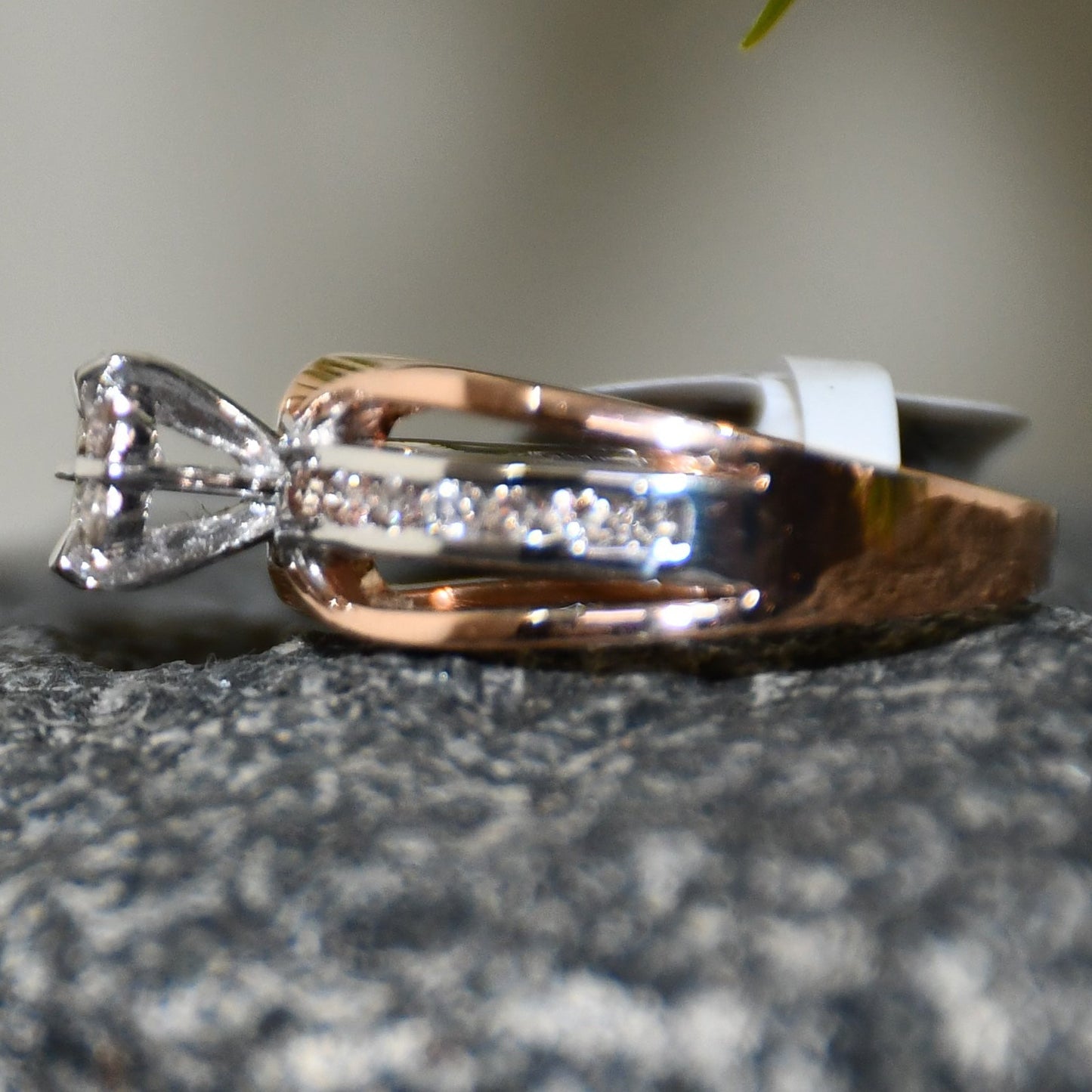 A diamond band ring with 14K gold hallmark, displayed on a black and grey rough surface.