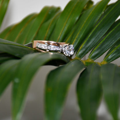A diamond band ring with 14K gold hallmark, displayed on green leaves.