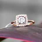 A gold band ring with a square-shaped, brilliant-cut diamonds centerpiece, set on a red surface.