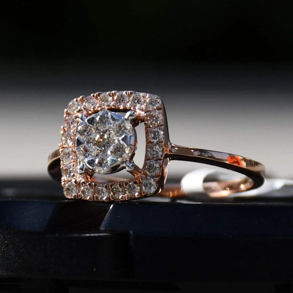A gold band ring with a square-shaped, brilliant-cut diamonds centerpiece, set on a black surface.
