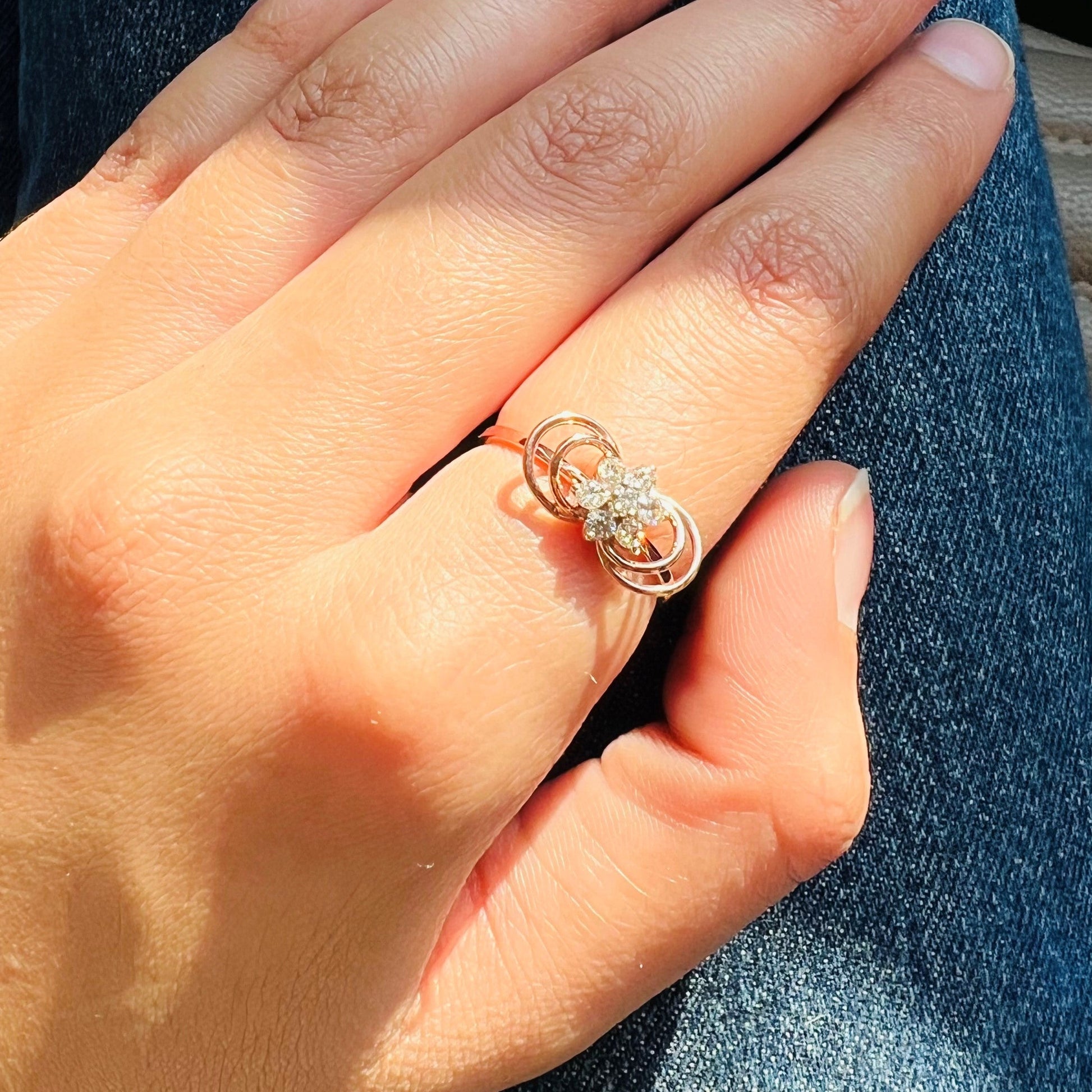 Delicate rose gold ring featuring a floral cluster of round diamonds at the center, showcased on a hand's finger.