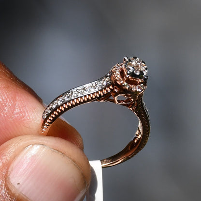 Close-up of a gold diamond ring holding on finger, featuring a round-cut center diamond surrounded by a delicate halo and a tapered band accented with small pavé-set diamonds and fine milgrain detailing.