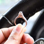 Close-up of a gold diamond ring holding with fingers, featuring a round-cut center diamond surrounded by a delicate halo and a tapered band accented with small pavé-set diamonds and fine milgrain detailing.