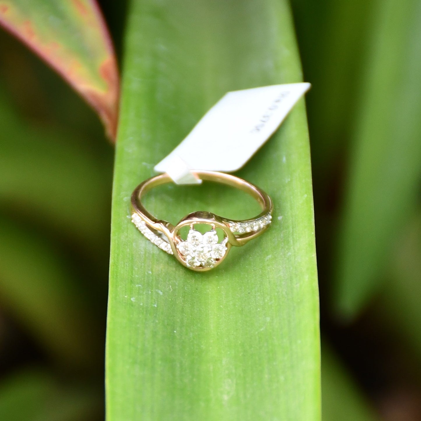 A 14kt gold diamond band ring with three brilliant cut natural diamonds on long green leaves.