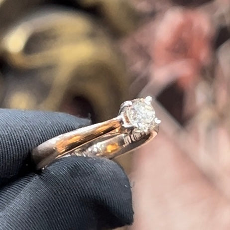 A person's hand is showing a solitaire diamond ring against a natural background where diamond is set in prong setting.