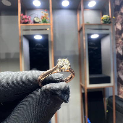 A person's hand is showing a solitaire diamond ring against a natural background where diamond is set in prong setting.