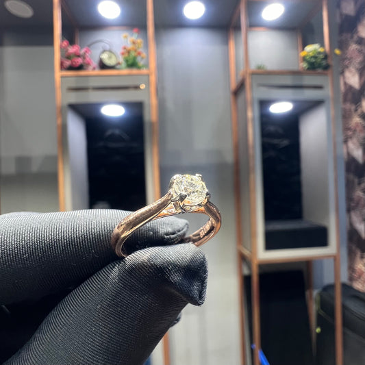 A person's hand is showing a solitaire diamond ring against a natural background where diamond is set in prong setting.