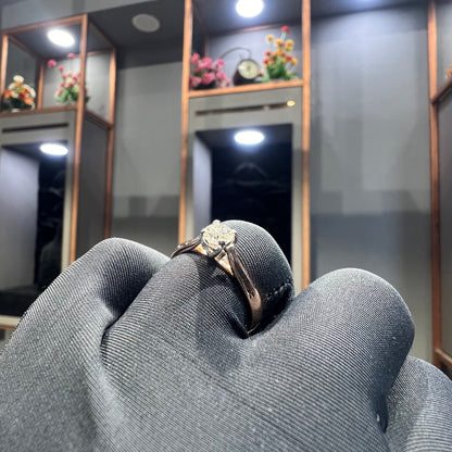 A person's hand is showing a solitaire diamond ring against a natural background where diamond is set in prong setting.