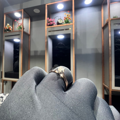 A person's hand is showing a solitaire diamond ring against a natural background where diamond is set in prong setting.