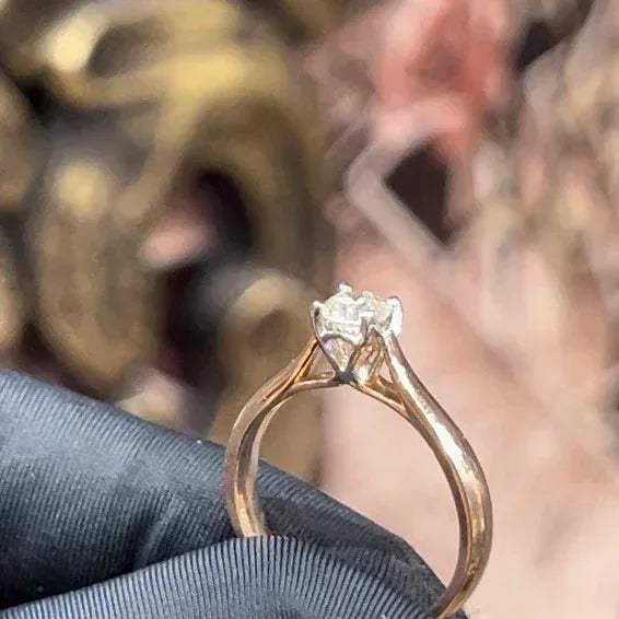 A person's hand is holding a solitaire diamond ring where diamond is set in prong setting.