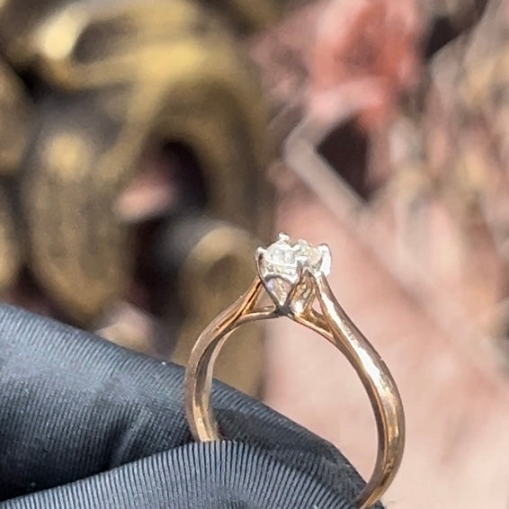 A person's hand is holding a solitaire diamond ring where diamond is set in prong setting.