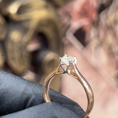 A person's hand is holding a solitaire diamond ring where diamond is set in prong setting.