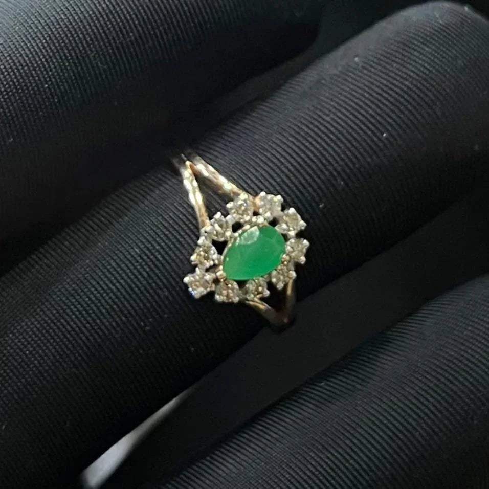 A handcrafted natural diamond solid gold ring, featuring a brilliant cut green stone centerpiece, surrounded by smaller clear diamonds, set on a black mannequin hand.
