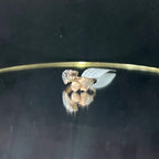 A ring with a gold band and a central natural diamonds, displayed on a reflective surface.