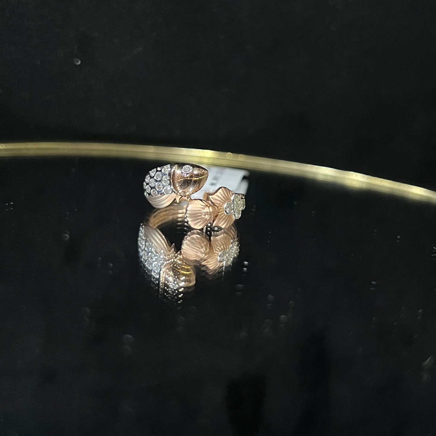 A ring with a gold band and a central natural diamonds, displayed on a reflective surface.