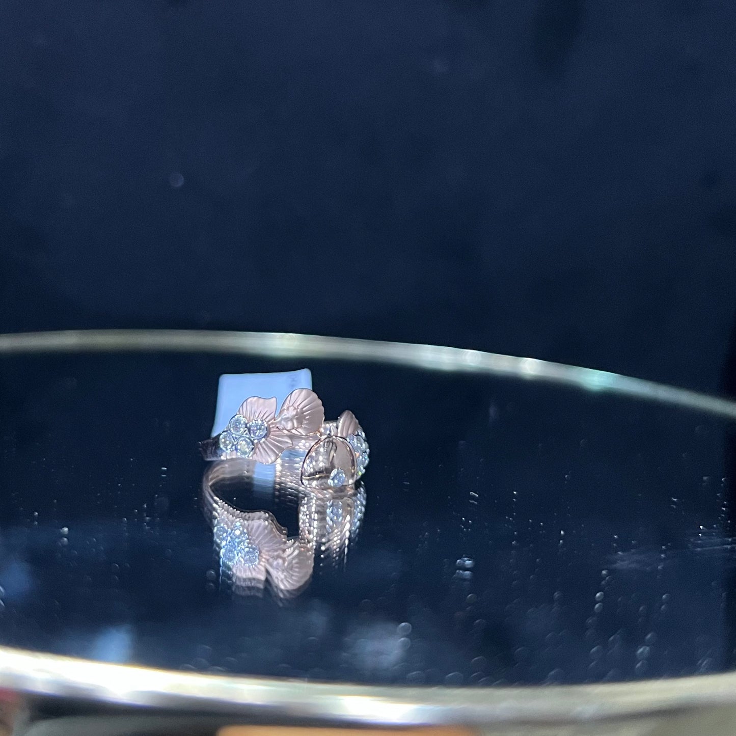 A ring with a gold band and a central natural diamonds, displayed on a reflective surface.