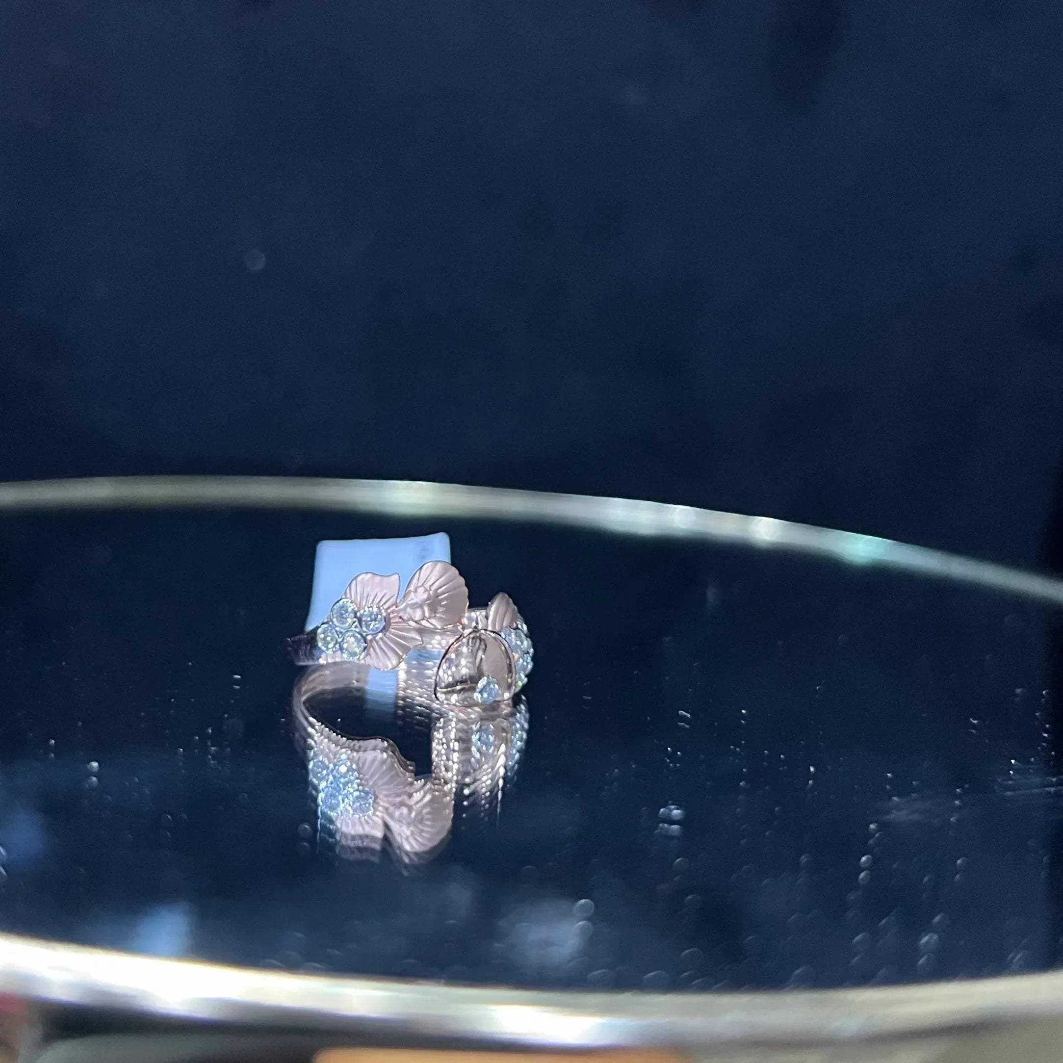 A ring with a gold band and a central natural diamonds, displayed on a reflective surface.