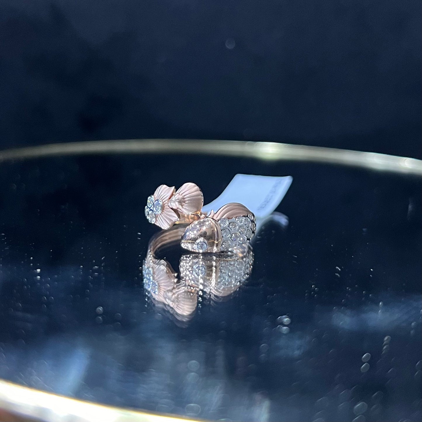 A ring with a gold band and a central natural diamonds, displayed on a reflective surface.