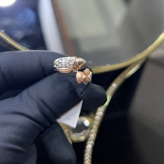 A ring with a gold band and a central natural diamonds, held by a hand with a black glove, with a reflective surface in the background.