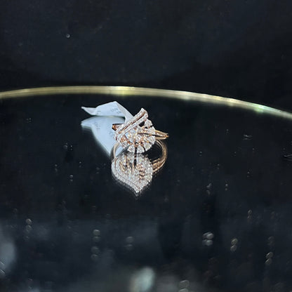 A handcrafted natural diamond solid gold ring displayed on a reflective surface, with a brilliant cut diamond in a gold band.
