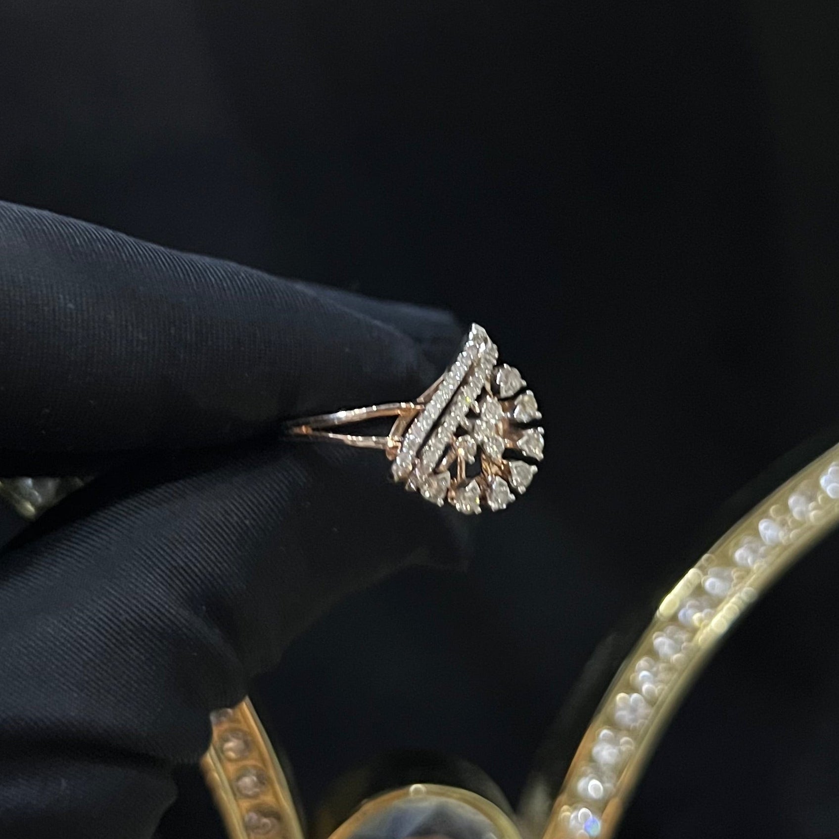 A handcrafted natural diamond solid gold ring held by a hand, with a brilliant cut diamond in a gold band.