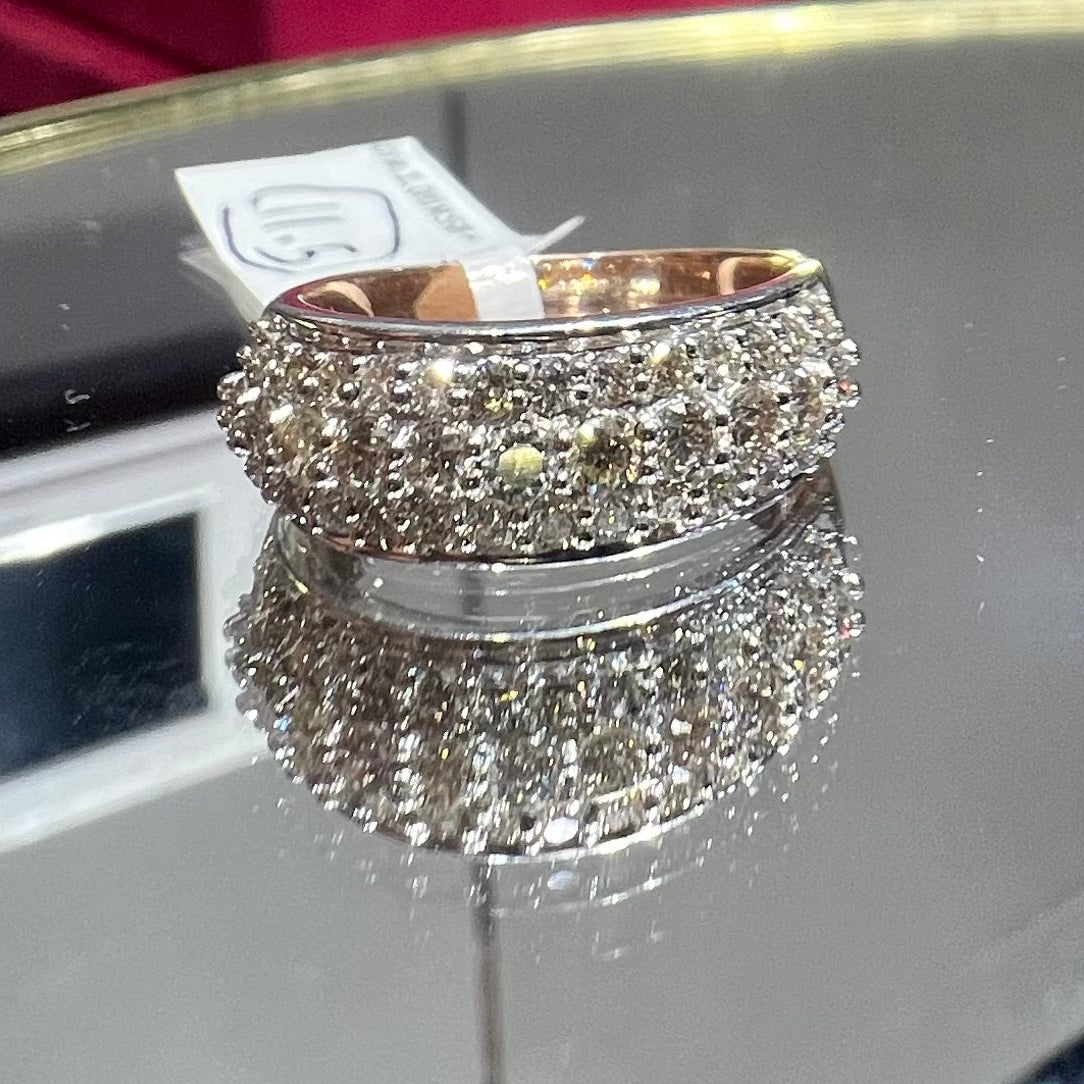 Close-up of a wide diamond band ring, featuring multiple rows of sparkling round-cut diamonds set in gold, displayed on a reflective surface.