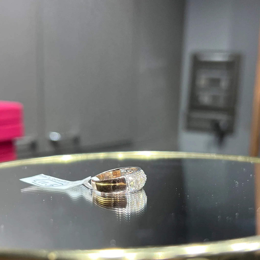 Close-up of a wide diamond band ring, featuring multiple rows of sparkling round-cut diamonds set in gold, displayed on a reflective surface.