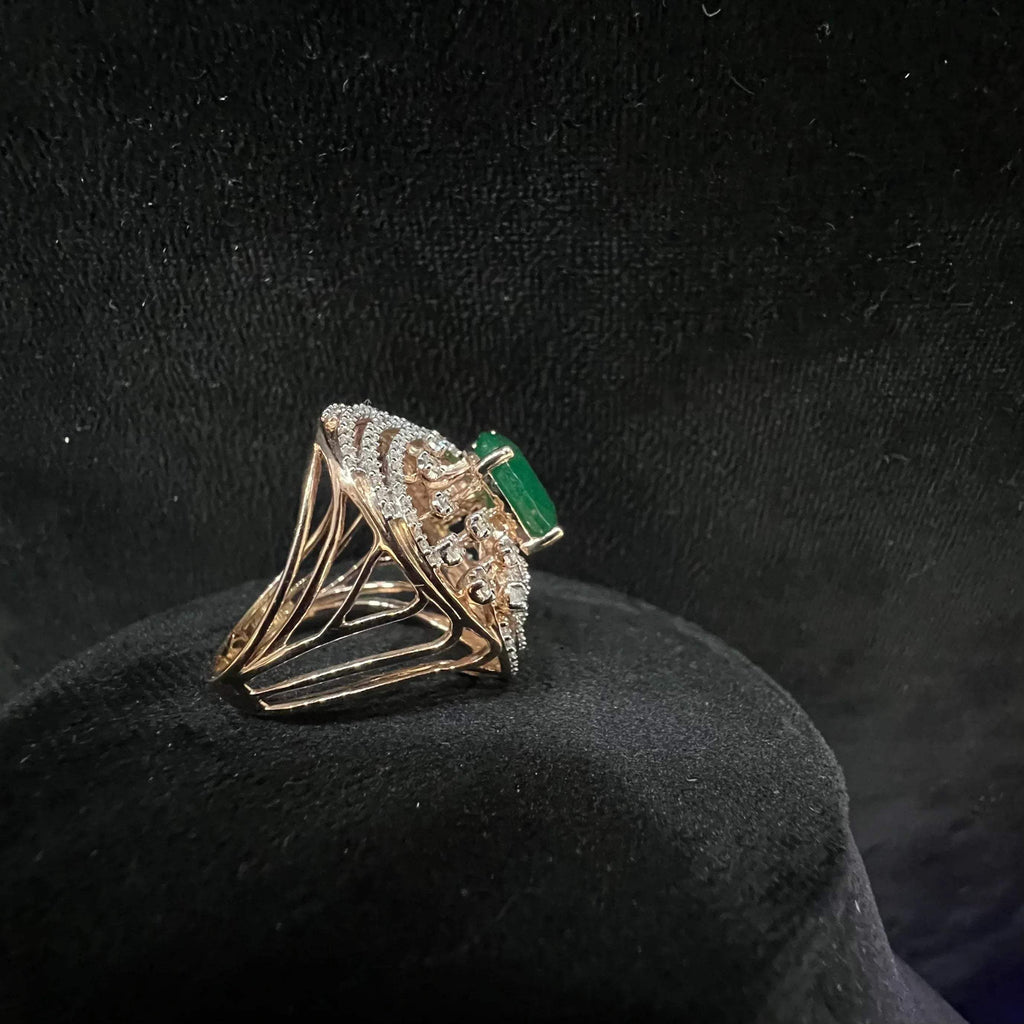 Close-up of an elegant statement ring featuring a large oval green gemstone at the center, surrounded by concentric circles of sparkling white diamonds set in a gold base against a black background.